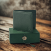 A green leather wallet from The Karigar Nepal is placed above the green box in a wooden table.