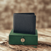 A picture of Black leather wallet from The Karigar Nepal is placed on a green box in a wooden table.
