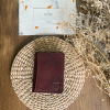 A unisex brown slim leather wallet placed in a wooden table.
