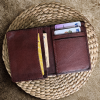 A unisex brown slim leather wallet placed in a wooden table.