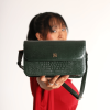 A girl in a red dress posing with Elira Green leather bag.