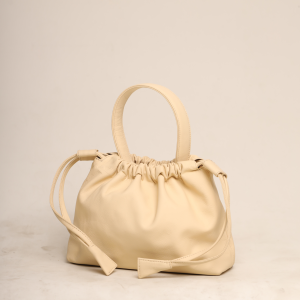 A Sand Beige handcrafted leather Thaili bag showing its unique gathered texture and minimalist top handle, created by The Karigar Nepal.